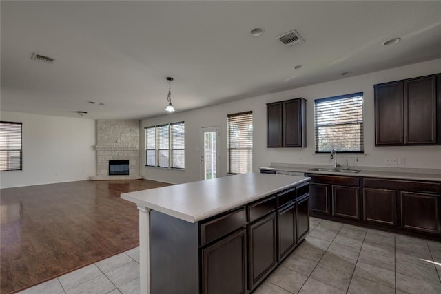 kitchen with a center island, sink, hanging light fixtures, light tile patterned floors, and a fireplace