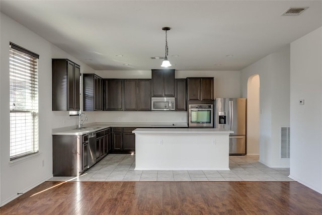 kitchen with hanging light fixtures, appliances with stainless steel finishes, a kitchen island, and plenty of natural light