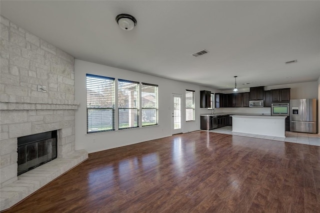 unfurnished living room featuring wood-type flooring, a stone fireplace, and sink