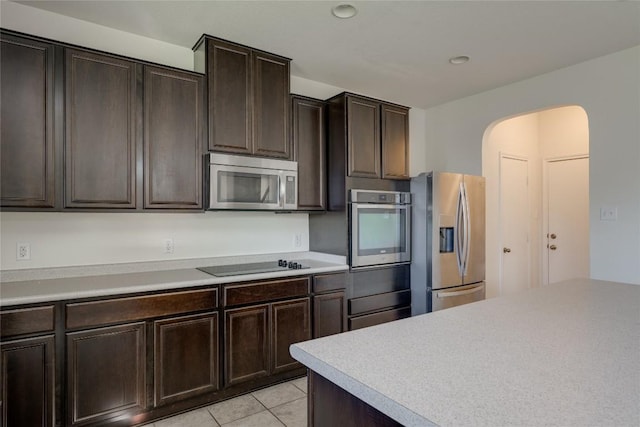 kitchen with light tile patterned flooring, dark brown cabinetry, and appliances with stainless steel finishes