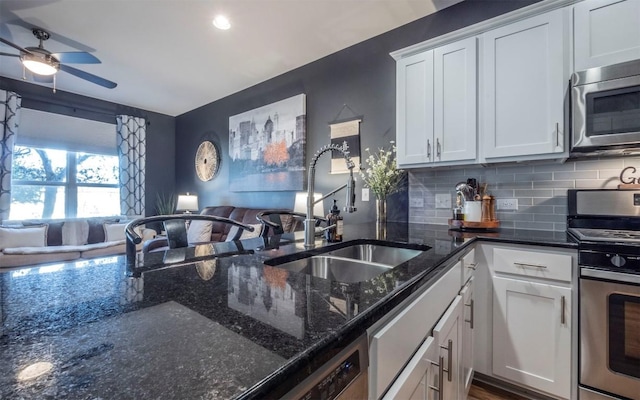 kitchen with dark stone counters, white cabinetry, sink, and stainless steel appliances