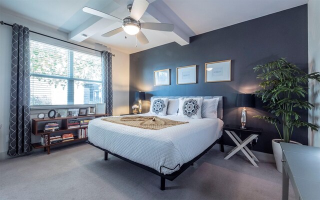 carpeted bedroom featuring beamed ceiling and ceiling fan