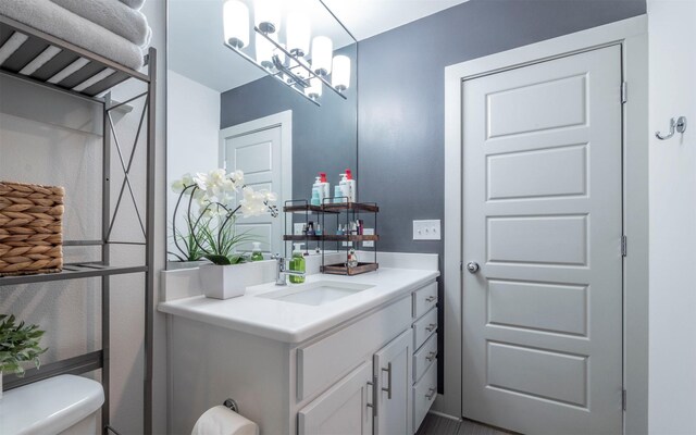 bathroom featuring vanity, toilet, and a notable chandelier