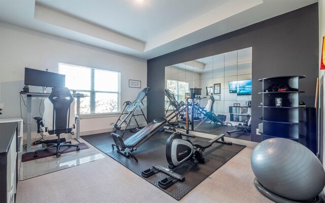 workout area with a tray ceiling and carpet floors