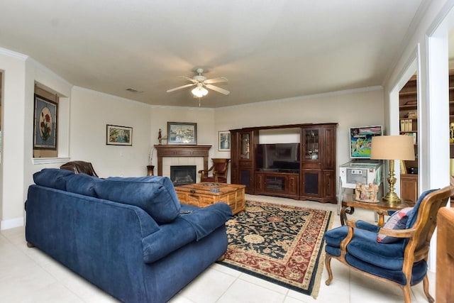 living room with ceiling fan, ornamental molding, a fireplace, and light tile patterned floors