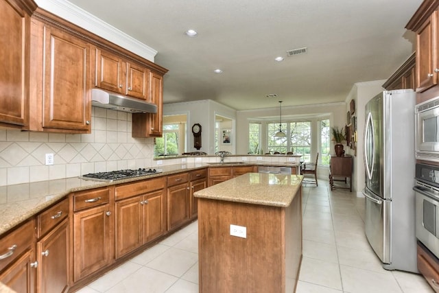 kitchen featuring light stone countertops, sink, a center island, tasteful backsplash, and appliances with stainless steel finishes