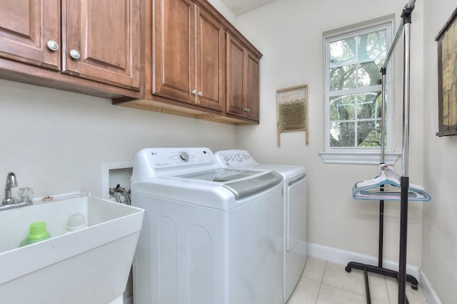 laundry area with washing machine and clothes dryer, sink, light tile patterned floors, and cabinets