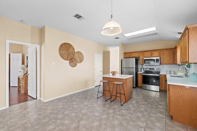 kitchen with appliances with stainless steel finishes, sink, light tile patterned floors, decorative light fixtures, and a center island