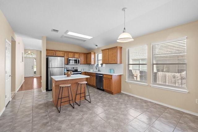 kitchen featuring appliances with stainless steel finishes, vaulted ceiling, sink, pendant lighting, and a kitchen island