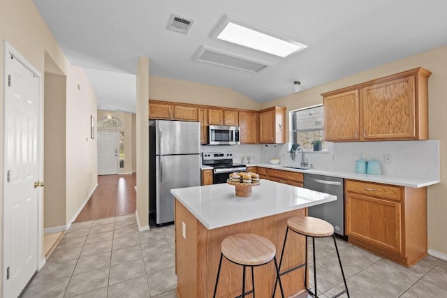 kitchen featuring a kitchen bar, stainless steel appliances, sink, light tile patterned floors, and a kitchen island