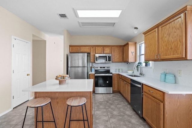 kitchen featuring a breakfast bar, sink, tasteful backsplash, a kitchen island, and stainless steel appliances