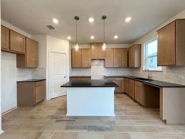 kitchen with sink, hanging light fixtures, a center island, and backsplash