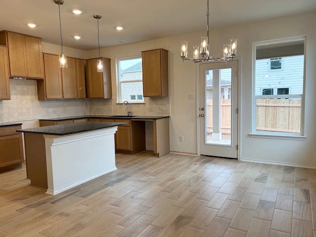 kitchen featuring sink, decorative light fixtures, light wood-type flooring, and a kitchen island