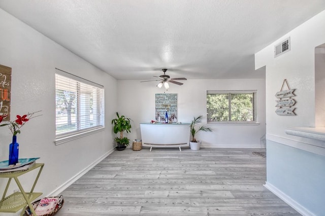 interior space featuring ceiling fan, light hardwood / wood-style floors, and a textured ceiling