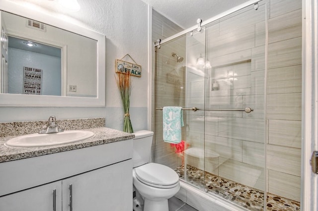 bathroom with an enclosed shower, vanity, toilet, and a textured ceiling