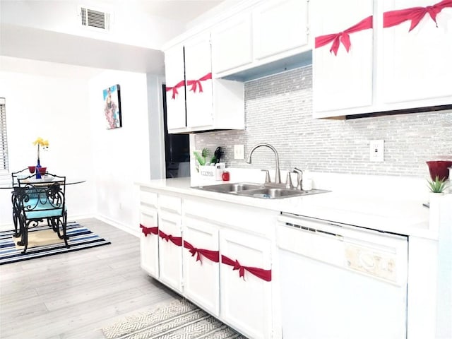 kitchen featuring decorative backsplash, white cabinets, sink, light hardwood / wood-style flooring, and dishwasher