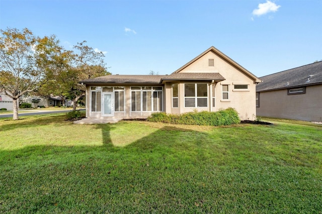 rear view of property with a lawn and a sunroom