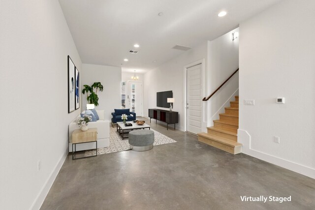 living room with concrete floors and an inviting chandelier