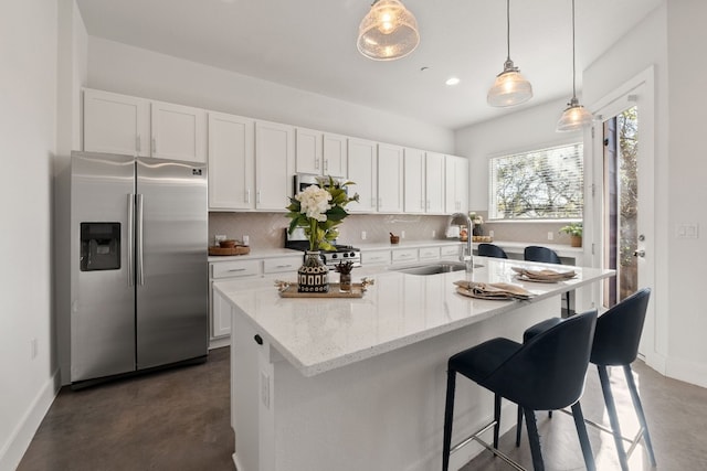 kitchen with tasteful backsplash, white cabinetry, sink, a kitchen island with sink, and stainless steel appliances