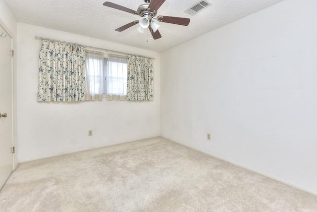 carpeted spare room featuring ceiling fan and a textured ceiling