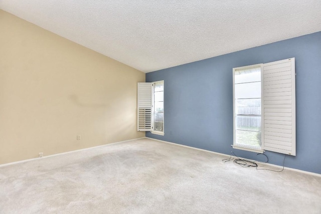 empty room with a textured ceiling, carpet flooring, and lofted ceiling