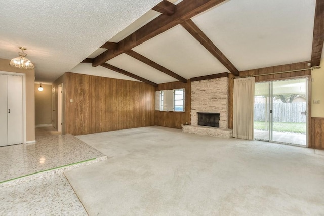 unfurnished living room with a fireplace, a textured ceiling, a wealth of natural light, and wooden walls