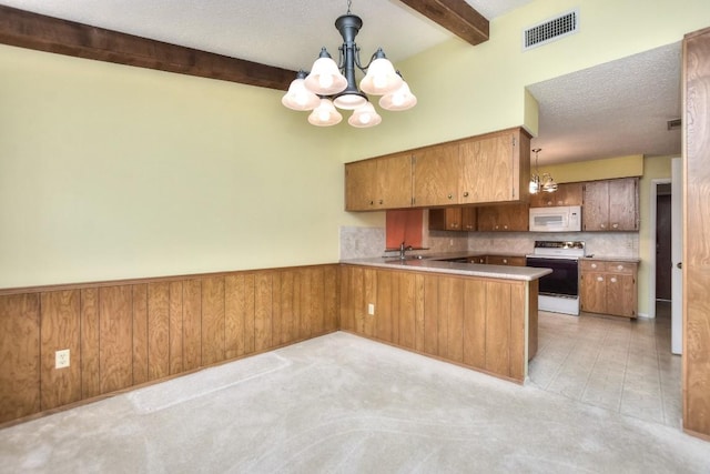 kitchen featuring kitchen peninsula, white appliances, beam ceiling, decorative light fixtures, and a chandelier