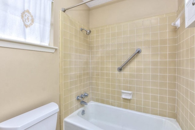 bathroom with tiled shower / bath combo and toilet