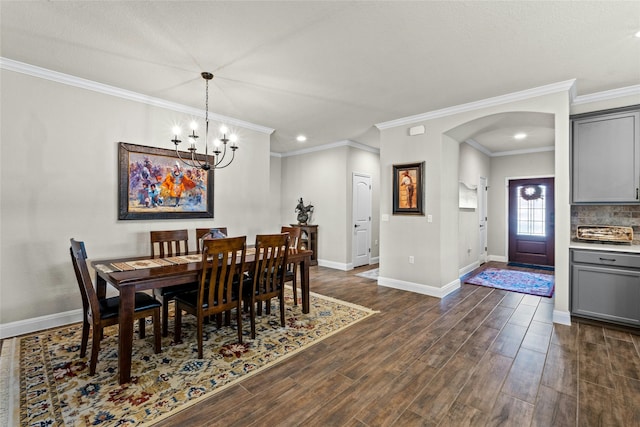 dining room with arched walkways, baseboards, ornamental molding, dark wood-style floors, and an inviting chandelier