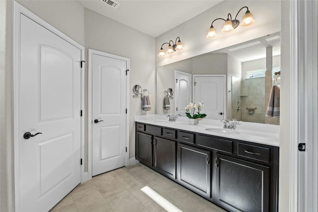 bathroom featuring double vanity, a walk in shower, a sink, and tile patterned floors