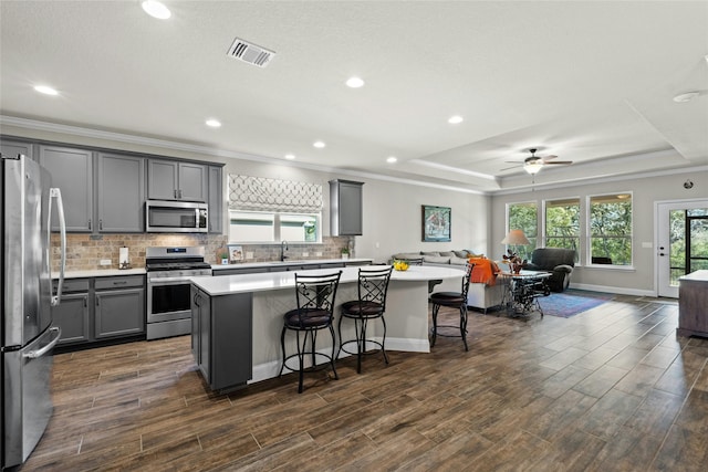 kitchen featuring light countertops, appliances with stainless steel finishes, a kitchen island, and a breakfast bar