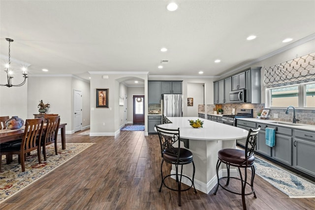 kitchen featuring stainless steel appliances, light countertops, a sink, and a kitchen island