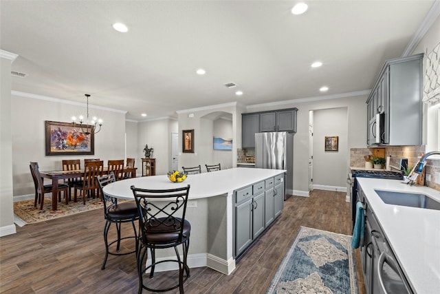 kitchen with tasteful backsplash, a kitchen island, appliances with stainless steel finishes, light countertops, and gray cabinetry