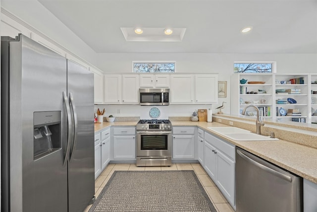 kitchen featuring white cabinets, a tray ceiling, stainless steel appliances, sink, and light tile patterned floors