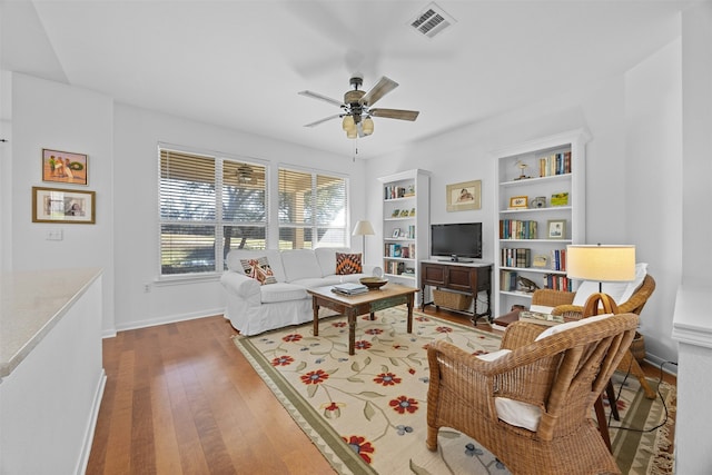 living room with ceiling fan, built in features, and wood-type flooring