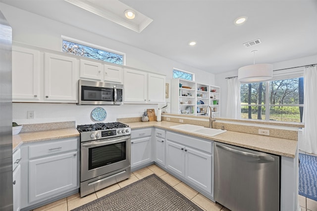 kitchen featuring kitchen peninsula, stainless steel appliances, decorative light fixtures, white cabinets, and sink