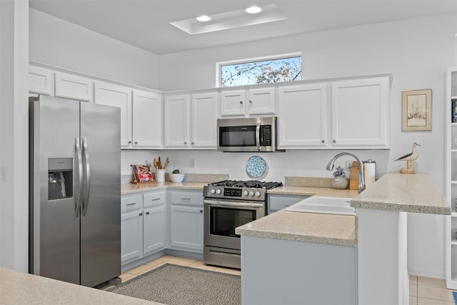 kitchen with white cabinets, appliances with stainless steel finishes, sink, kitchen peninsula, and light tile patterned flooring