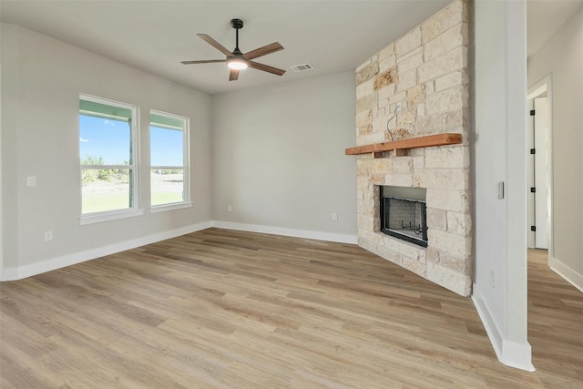 unfurnished living room featuring a stone fireplace, ceiling fan, and light hardwood / wood-style floors