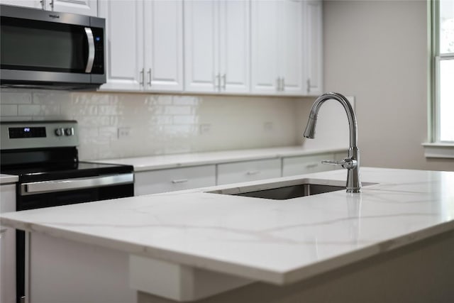 kitchen with light stone countertops, white cabinets, and stainless steel appliances