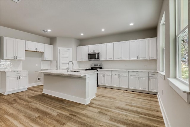 kitchen featuring an island with sink, sink, white cabinets, and stainless steel appliances