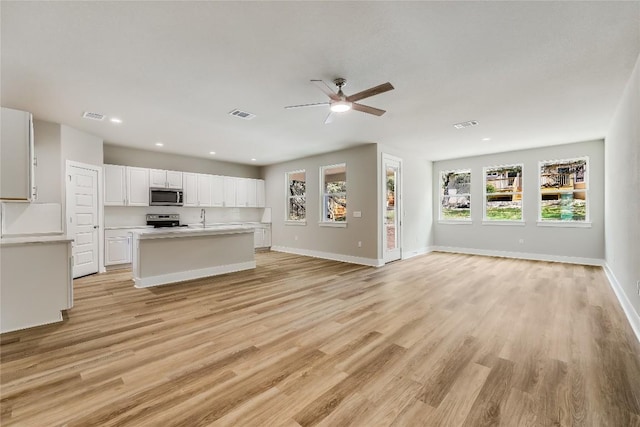 kitchen featuring appliances with stainless steel finishes, ceiling fan, white cabinets, a center island, and light hardwood / wood-style floors