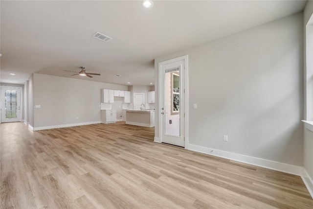 unfurnished living room featuring light hardwood / wood-style flooring, ceiling fan, and sink