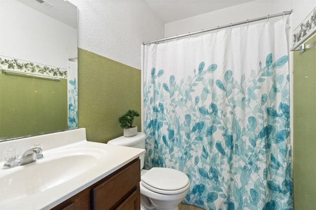 full bathroom featuring curtained shower, a textured wall, vanity, and toilet