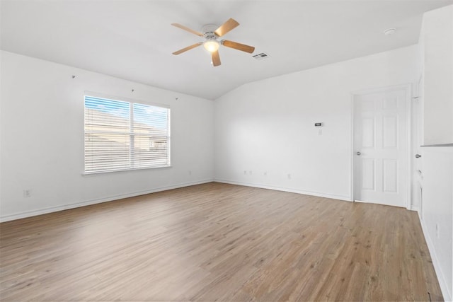 spare room featuring lofted ceiling, visible vents, baseboards, a ceiling fan, and light wood-style floors