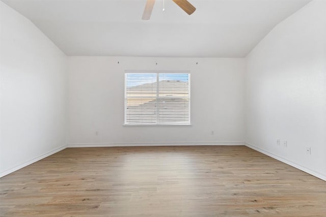 spare room featuring baseboards, light wood-type flooring, vaulted ceiling, and ceiling fan