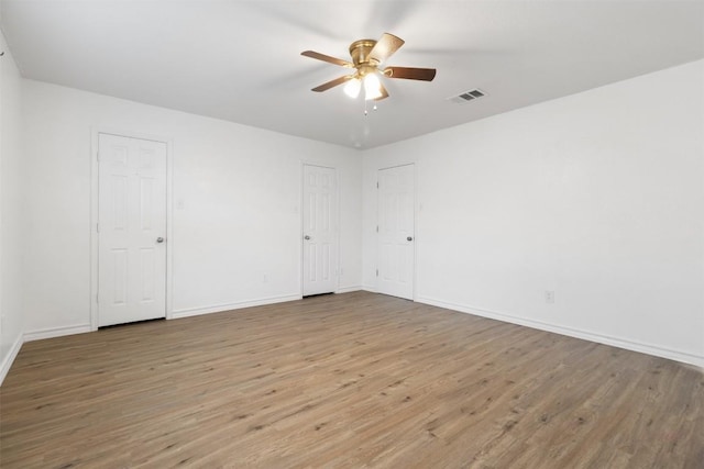 unfurnished room with a ceiling fan, visible vents, light wood-style flooring, and baseboards