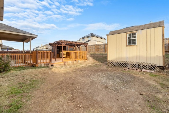 view of yard featuring a storage shed, a fenced backyard, an outbuilding, and a wooden deck