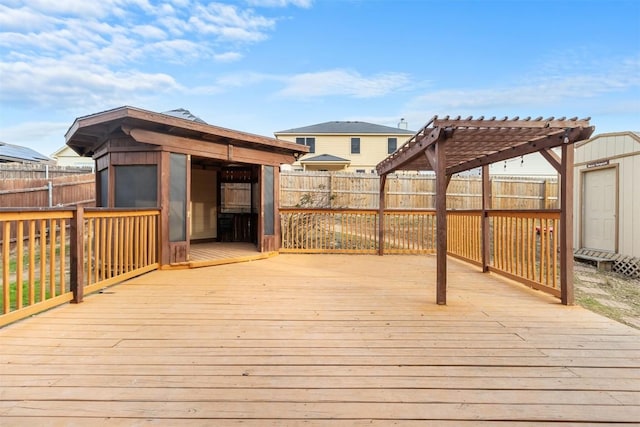 deck featuring a gazebo, a fenced backyard, a pergola, and an outdoor structure