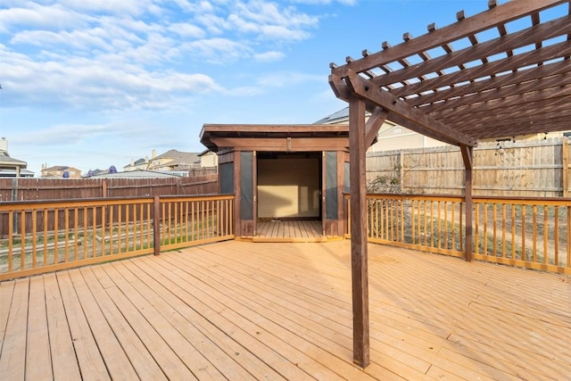 wooden deck with a fenced backyard, an outdoor structure, a storage unit, and a pergola