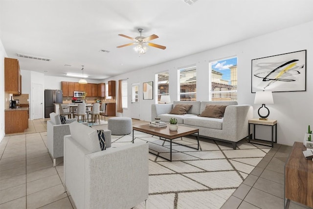 living room with light tile patterned floors, visible vents, and a ceiling fan